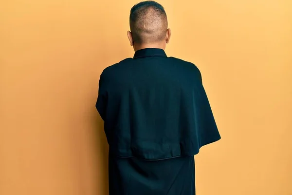 Junger Lateinischer Priester Steht Auf Gelbem Hintergrund Und Blickt Rückwärts — Stockfoto