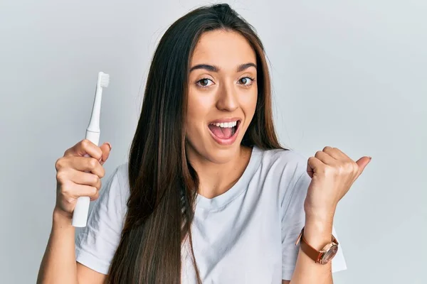 Menina Hispânica Jovem Segurando Escova Dentes Elétrica Apontando Polegar Até — Fotografia de Stock