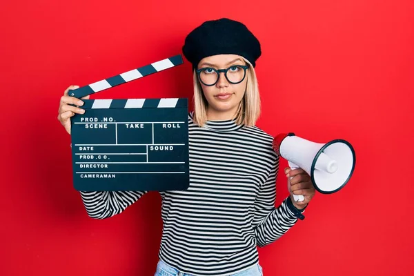 Krásná Blondýnka Drží Video Film Clapboard Megafon Skeptický Nervózní Zamračený — Stock fotografie