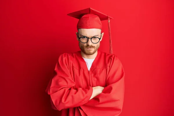 Young Redhead Man Wearing Red Graduation Cap Ceremony Robe Skeptic — Stock Photo, Image