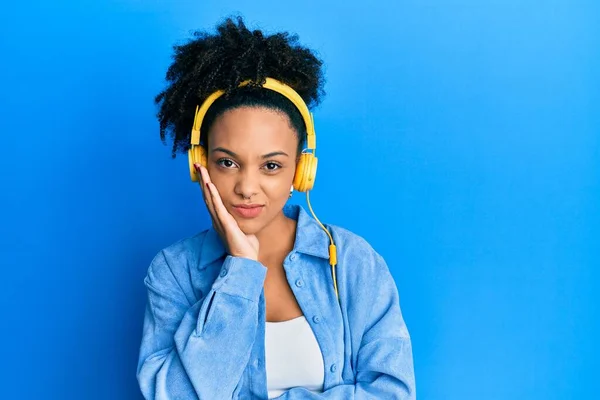 年轻的非洲裔美国女孩 一边用耳机听音乐 一边觉得自己疲惫不堪 并对交叉双臂的抑郁症感到厌烦 — 图库照片