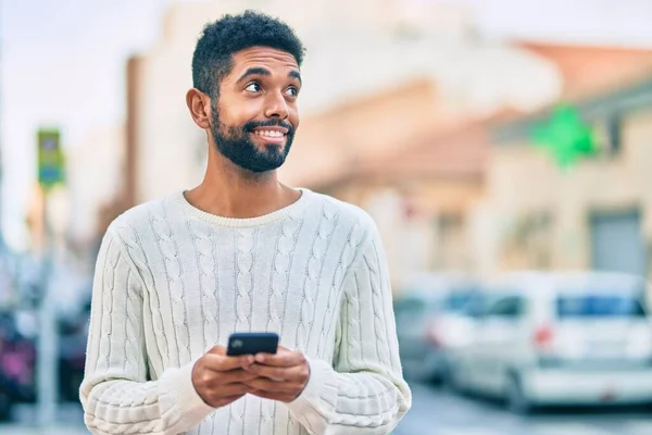 若いアフリカ系アメリカ人の男が市内のスマートフォンを使って笑顔で — ストック写真