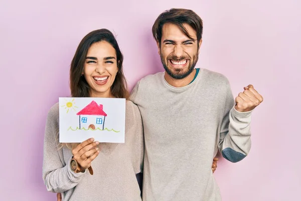 Casal Hispânico Jovem Segurando Casa Desenhar Gritando Orgulhoso Celebrando Vitória — Fotografia de Stock