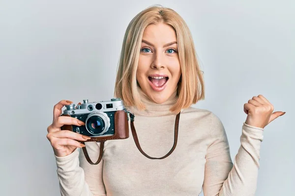 Młoda Blondynka Trzyma Vintage Aparat Wskazując Kciuk Górę Boku Uśmiechając — Zdjęcie stockowe