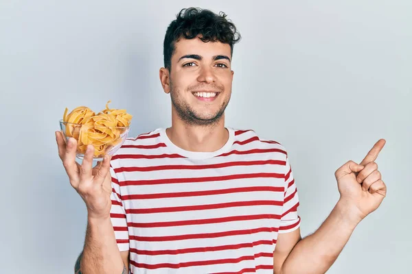Jonge Spaanse Man Die Een Kom Vasthoudt Met Ongekookte Pasta — Stockfoto