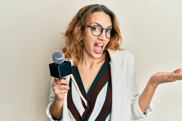 Young Caucasian Woman Holding Reporter Microphone Celebrating Achievement Happy Smile — Stock Photo, Image