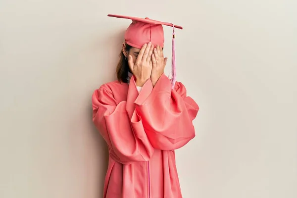 泣きながら手で顔を覆う悲しい表情で卒業キャップと儀式用のローブを着た若い白人女性 うつ病の概念 — ストック写真