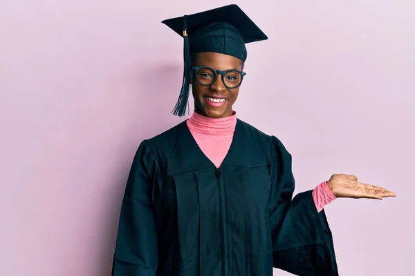 年轻的非洲裔美国女孩戴着毕业典礼帽 身穿婚纱 面带微笑 手牵着手看着摄像机 — 图库照片