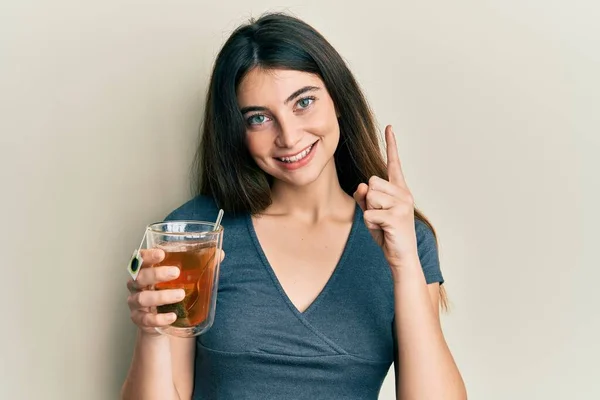 若い白人女性は 幸せな顔をしたアイデアや質問を指差す指で笑顔のお茶のカップを保持 ナンバーワン — ストック写真