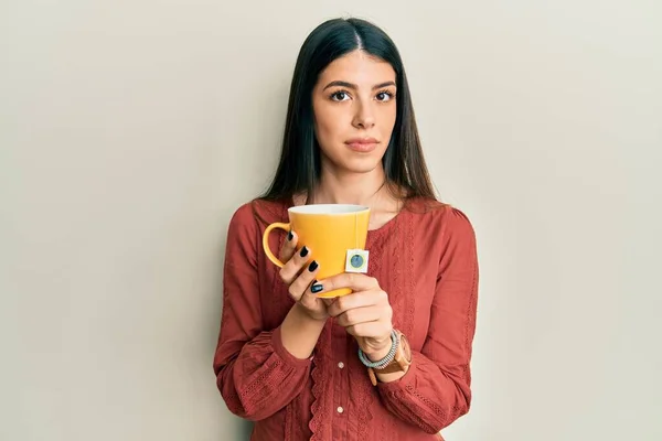 Mujer Hispana Joven Sosteniendo Taza Relajado Con Expresión Seria Cara —  Fotos de Stock