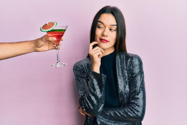 Seksi parti ceketi giyen ve İspanyol kolu sunan genç bir kız şüphe üzerine yoğunlaşmış, çenesinde parmak olan ve kafasını kaldırıp merak eden bir kokteyl düşünüyor. 