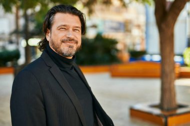 Orta yaşlı işadamı şehirde mutlu mesut dikilirken.