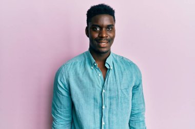 Yakışıklı, sıradan kıyafetler giyen, mutlu ve havalı bir gülümsemesi olan siyahi bir adam. şanslı kişi. 