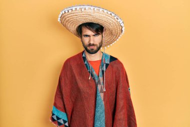 Meksikalı şapkalı, kuşkucu ve gergin genç İspanyol bir adam sorun yüzünden surat asıyor. negatif kişi. 