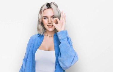 Sıradan kıyafetler giyen, pozitif gülümseyen genç sarışın kız el ve parmaklarıyla 