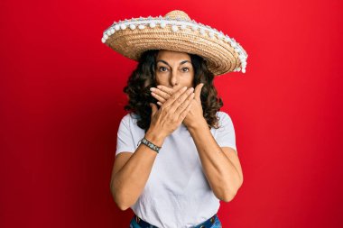 Meksika şapkası tutan orta yaşlı İspanyol kadın yanlışlıkla elleri ile ağzını kapatırken şok oldu. gizli kavram. 