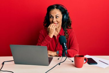 Radyo stüdyosunda çalışan orta yaşlı güzel bir kadın gergin ve gergin görünüyor. Elleri ağızdan tırnak yiyor. anksiyete. 