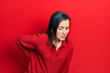 Orta yaşlı İspanyol kadın gündelik kıyafetler giyiyor sırt ağrısı çekiyor, elleriyle dokunuyor, kas ağrısı çekiyor. 