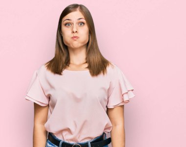 Gündelik kıyafetler giyen, komik yüzlü, yanak şişiren güzel beyaz bir kadın. Havayla şişmiş ağız, çılgın bir ifade.. 