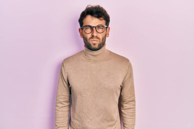 Balıkçı yaka kazak giyen, gözlüklü, kuşkucu ve gergin sakallı yakışıklı bir adam. Problemden dolayı surat asıyor. negatif kişi. 