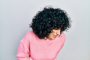 Orta Doğulu genç bir kadın gündelik kıyafetler giyiyor sırt ağrısı çekiyor, elleriyle dokunuyor, kas ağrısı çekiyor. 