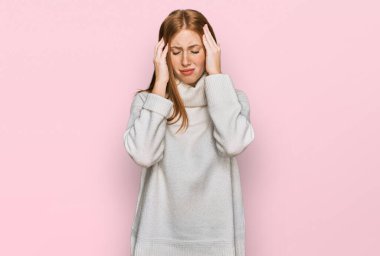 Genç İrlandalı kadın, elleri kafasında, günlük bir kazak giyiyor. Stres yüzünden başı ağrıyor. migren ağrısı. 