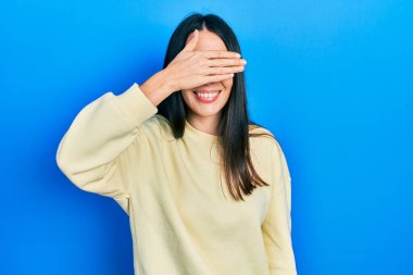 Genç esmer kadın, sıradan bir kazak giyiyor, gülümsüyor ve elleri yüzünde, şaşırtmak için gözleri kapatıyordu. kör kavram. 