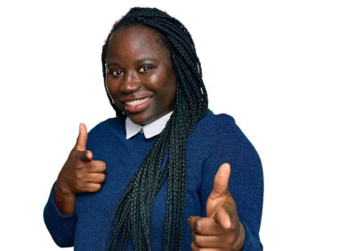 Saçları örgülü genç siyahi kadın mutlu ve komik yüzüyle kamerayı işaret ediyor. iyi enerji ve titreşimler. 