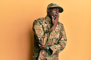 Asker üniforması giyen genç Afro-Amerikan adam ağzını eliyle kapatmaktan sıkılmış. Huzursuz ve uykulu.. 