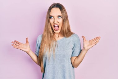 Sıradan tişörtler giyen genç sarışın kız deli gibi bağırıyor ve agresif bir ifade ve kollarla bağırıyor. hüsran kavramı. 