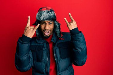 Sakallı, kışlık şapkalı ve ceketli, çılgın bir ifadeyle bağıran, elleri havada rock sembolü yapan Afrikalı genç bir Amerikalı. Müzik yıldızı. ağır kavram. 