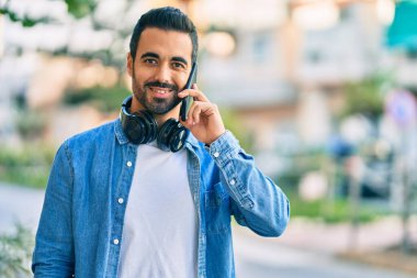 Genç İspanyol adam gülümsüyor. Şehirdeki akıllı telefondan konuşuyor..