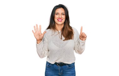 Güzel İspanyol kadın gündelik süveter giyer ve altı numaralı parmaklarıyla işaret ederken kendinden emin ve mutlu gülümserdi.. 