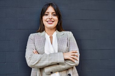 Genç İspanyol iş kadını şehirde çapraz hareketlerle mutlu gülümsüyor..