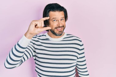 Orta yaşlı, günlük kıyafetler giyen, gülümseyen, kendine güvenen, el hareketi yapan, parmaklarıyla işaret yapan ve kameraya bakan beyaz bir adam. ölçüm kavramı. 