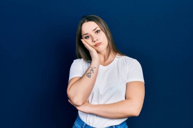 Günlük beyaz tişört giyen genç İspanyol kız kollarını kavuşturup depresyondan sıkılmış ve yorgun görünüyor.. 