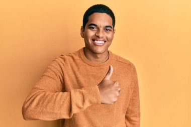 Sıradan bir kazak giyen genç, yakışıklı İspanyol adam elleriyle mutlu bir jest yapıyor. Kameraya bakıp başarıyı gösteren ifade. 