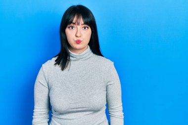 Günlük kıyafetler giyen genç İspanyol kadın komik yüzlü yanakları şişiriyor. Havayla şişmiş ağız, çılgın bir ifade.. 