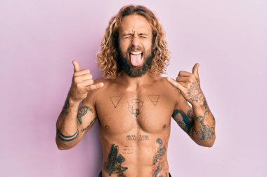 Sakallı, uzun saçlı, tişörtsüz, dövmesi olmayan, Shaka yazan, dilini dışarı çıkaran yakışıklı bir adam.. 