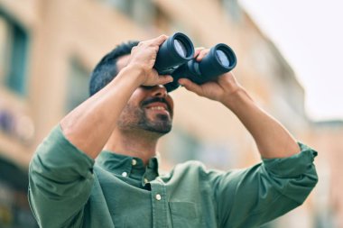 Genç İspanyol gülümseyen adam şehirde dürbünle yeni bir fırsat arıyor..