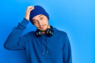 Eşofman altı ve kulaklık giyen İspanyol genç adam soru sorup kafasını karıştırıyor. Şüpheyle kararsız, kafa kafaya düşünerek. Düşünceli kavram. 