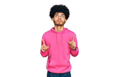 Afro saçlı, sıradan pembe tişörtlü, üzgün ve üzgün görünen, parmaklarıyla yön gösteren, mutsuz ve depresif genç Afro-Amerikalı bir adam.. 