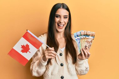 Güzel esmer, genç bir kadın elinde Kanada bayrağı ve dolarlarla kahkahalarla gülüyor.. 
