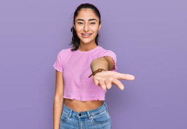 Diş teli takan, günlük kıyafetler giyen neşeli gülümseyen, yardım eli uzatan ve kabul gören İspanyol genç kız.. 