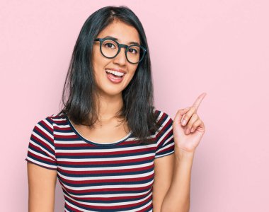 Güzel Asyalı genç bir kadın. Günlük kıyafetler ve gözlük takıyor. Yüzünde kocaman bir gülümseme var.. 