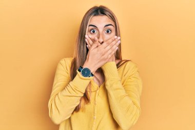 Gündelik sarı kazak giyen güzel İspanyol kadın yanlışlıkla elleri ile ağzını kapatırken şok oldu. gizli kavram. 