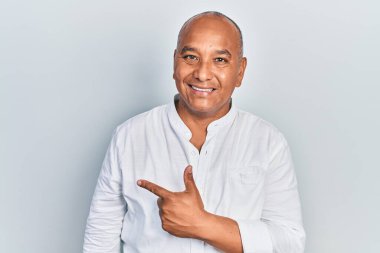 Orta yaşlı, gündelik kıyafetler giyen, neşeli, yüzünde mutlu ve doğal bir ifade olan, elleri ve parmaklarıyla yüzünü gösteren bir gülümseme olan Latin bir adam. 