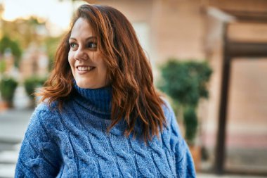 Genç İrlandalı artı cüsseli kız gülümseyerek şehirde mutlu mesut duruyor..