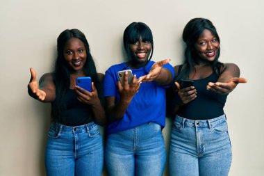 Üç Afro-Amerikalı arkadaş akıllı telefon kullanıyor gülümseyerek el sıkışarak selamlama ve hoş geldin diyorlar. başarılı iş. 