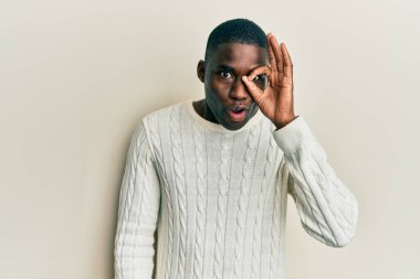 Genç Afro-Amerikan bir adam günlük giysiler giyiyor. Şaşırmış yüz ifadesiyle şaşırmış, parmaklarının arasından bakıyor. İnançsız ifade. 